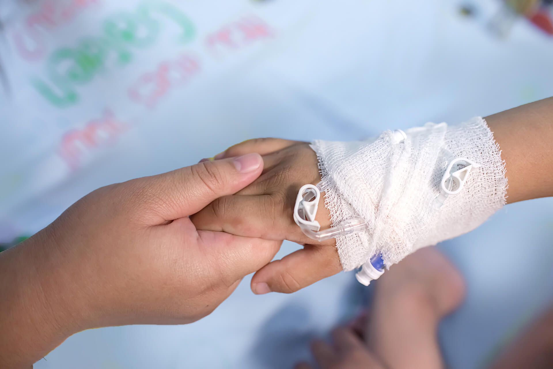 holding child's hand with IV